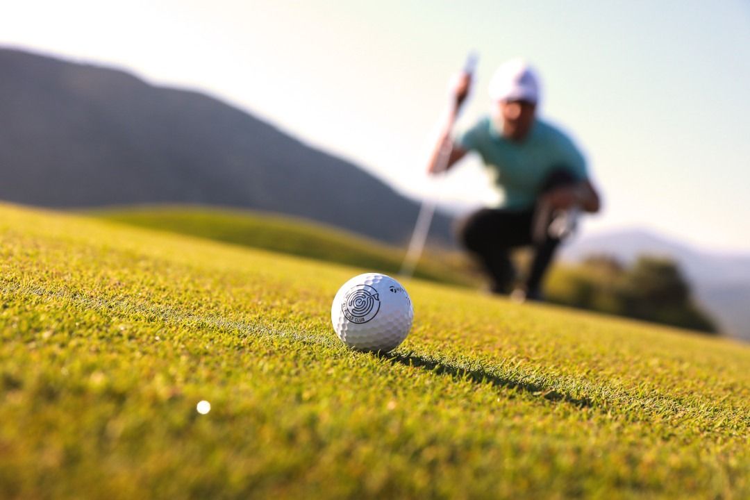 A golf ball being focused with a golfer in the background